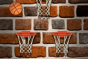 Ceglana ściana z trzema obręczami do koszykówki i piłką