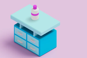 Niebieska szafka z czterema szufladami i jasnozielonym blatem, na którym stoi biały pojemnik z fioletowym paskiem, na różowym tle