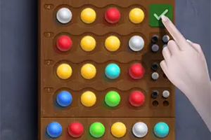 Drewniana plansza z kolorowymi kulkami w rzędach oraz ludzka dłoń naciskająca zielony przycisk z V