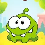 Zielony stworek z dużymi oczami i dwoma zębami na tle kolorowego krajobrazu z drzewami i budynkami