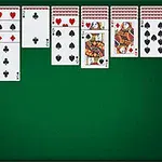 Karty do gry ułożone na zielonym tle w układzie pasjansa z widocznymi asami i damami