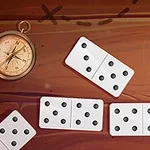 Kompas na drewnianym tle otoczony rozrzuconymi płytkami domina