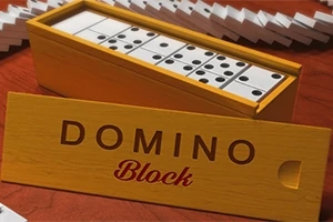 Drewniane pudełko z otwartym wiekiem, wypełnione kostkami domina, na tle pojedynczych kostek oraz napis DOMINO Block na pokrywie