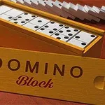Drewniane pudełko z otwartym wiekiem, wypełnione kostkami domina, na tle pojedynczych kostek oraz napis DOMINO Block na pokrywie