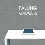Tablet leżący na białym stole na tle szarej ściany z napisem Falling Gadgets