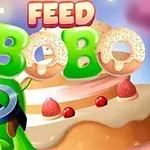 Zielony stworek w okularach z przodu, tło z ciastkiem i truskawkami, oraz napisy FEED BOBO