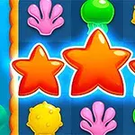 Trzy pomarańczowe gwiazdy otoczone różowymi koralami, zielonymi meduzami i żółtymi kulkami na niebieskiej siatce