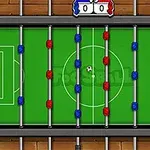 Widok z góry na stół do piłkarzyków z piłką na zielonym boisku i figurkami graczy w kolorach czerwonym i niebieskim