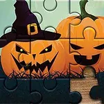 Dwie uśmiechnięte dynie z wyciętymi twarzami, jedna w kapeluszu czarownicy, w formie układanki z brakującym elementem na drewnianym tle