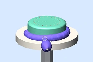 Fioletowy wałek dociskający się do turkusowego ciasta na dużym okrągłym stojaku