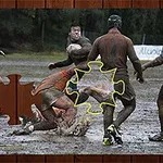 Grupa mężczyzn gra w rugby na błotnistym boisku, a na obrazie znajduje się brakujący element układanki