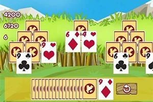 Karty do gry ułożone na tle zielonej trawy z górami w oddali