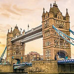 Tower Bridge w Londynie o zachodzie słońca, z widocznymi wieżami i fragmentem mostu, oraz zabudowania w tle