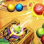 Kolorowe, zdobione kulki oraz strzelająca z działa kula w procesie uderzenia innych kul na planszy o wzorach azteckich