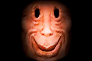 Twarz o ciemnych oczodołach i szerokim uśmiechu na czerwonawym tle