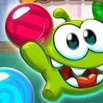 Zielony stworek z dużymi oczami otoczony kolorowymi kulami