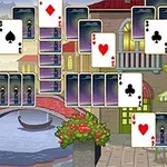 Karty do gry ułożone w rozmaitej formacji na tle malowniczego, weneckiego kanału z mostem i budynkami