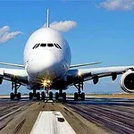 Duży samolot pasażerski widziany z przodu na pasie startowym, niebo z kilkoma chmurami w tle