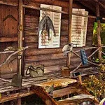 Drewniana chatka otoczona roślinnością z przymocowanymi narzędziami i przedmiotami na werandzie