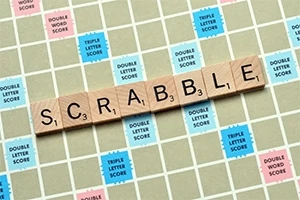 Płytki z literami układające słowo SCRABBLE na planszy z kolorowymi premiami punktowymi