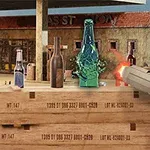 Osoba trzymająca pistolet strzela do butelek ustawionych na drewnianej skrzyni na tle pustynnego miasteczka