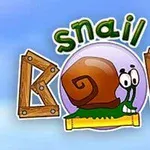 Ślimak o uśmiechniętej twarzy siedzący w otoczce napisu Snail Bob z drewnianymi elementami na tle błękitnego nieba