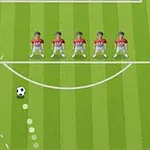 Piłkarze w czerwonych koszulkach ustawieni w murze na zielonym boisku z piłką do kopnięcia