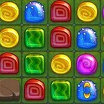 Kolorowe, błyszczące cukierki w siatce złożonej z prostokątów o różnych kształtach i kolorach, na zielonym tle