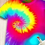 T-shirt w stylu tie-dye z kolorową spiralą na tle drewnianej powierzchni, z farbą w sprayu widoczną w prawym dolnym rogu
