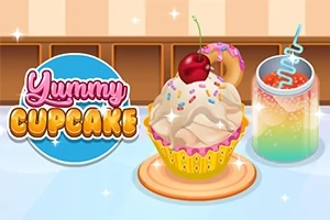 Babeczka z kremem, posypką i wiśnią na wierzchu obok kolorowego napoju z lodem i słomką na tle kuchennego blatu z napisem Yummy Cupcake